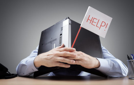 company crisis Person buried under computer holding a sign that reads "help."