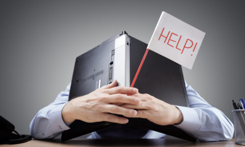 company crisis Person buried under computer holding a sign that reads "help."