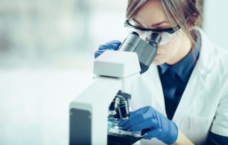 How does content marketing apply to a highly educated audience? Woman wearing googles and gloves looking into a microscope.