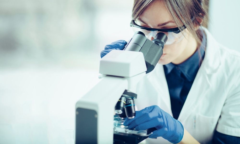 How does content marketing apply to a highly educated audience? Woman wearing googles and gloves looking into a microscope.