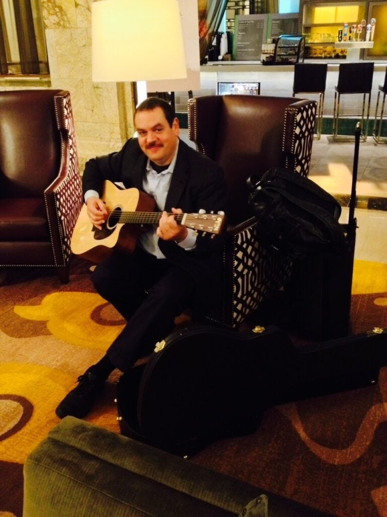 George Stenitzer with guitar in hotel lobby