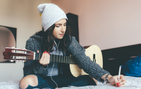 Woman writing song with guitar and paper