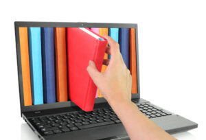 reader pulling a book out of a computer screen